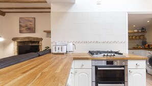 A modern kitchen with a wooden countertop, white cabinets, a built-in oven, and a gas stove. - Charming 3-Bed Cottage in Central Stroud (Gloucestershire)