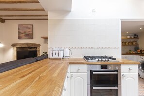 A modern kitchen with a wooden countertop, white cabinets, a built-in oven, and a gas stove.