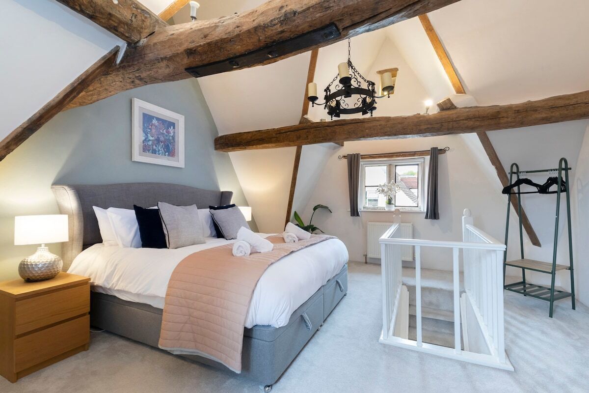 A bedroom with a bed, bedside table, lamp, and a window with curtains.