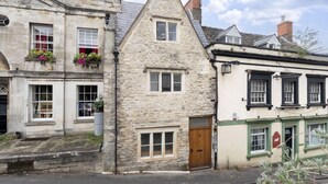A stone building with a wooden door labeled "twenty one," a window with a red sign, and a small window with a white frame. - Charming 3-Bed Cottage in Central Stroud (Gloucestershire)