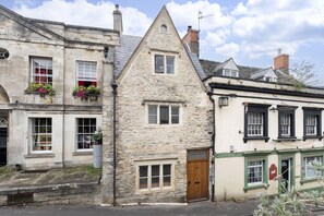 A stone building with a wooden door labeled "twenty one," a window with a red sign, and a small window with a white frame. - Charming 3-Bed Cottage in Central Stroud (Gloucestershire)