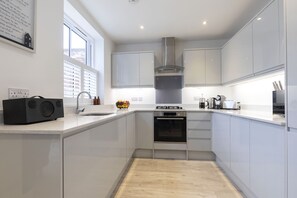 Una cocina moderna con armarios blancos, horno empotrado y ventana que ofrece luz natural.