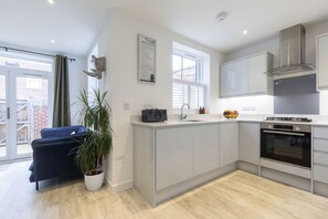 A modern kitchen with a built-in oven, a potted plant, and a blue sofa.