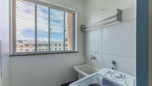 A small, compact bathroom with a window, a bathtub, and a washing machine. - Apart 450m From the Beach in Cond. w/ Pool Var0302 (Ilhéus)