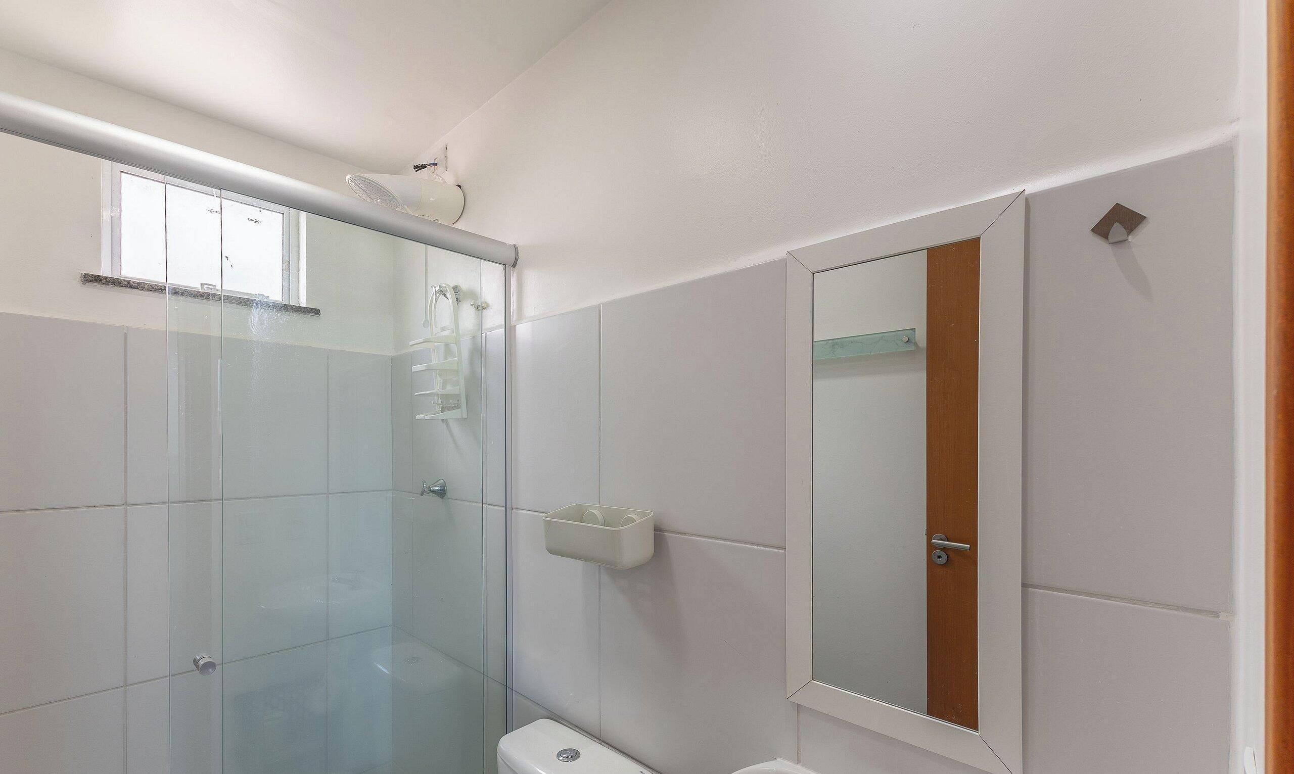 A bathroom with a glass shower enclosure, a white sink, and a mirror.