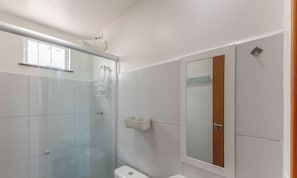 A bathroom with a glass shower enclosure, a white sink, and a mirror.