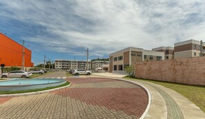 A modern building complex with a swimming pool, paved walkways, and parked cars. - Apart 450m From the Beach in Cond. w/ Pool Var0302 (Ilhéus)