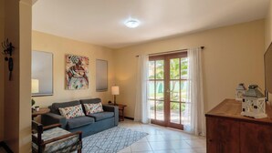 A living room with a sofa, a patterned rug, a wooden cabinet, and a view through a glass door. - Beautiful House With Pool & Barbecue Ura0015 (Porto Seguro)