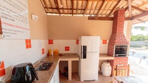 A compact kitchen with a refrigerator, a gas stove, and a brick oven. - Beautiful House With Pool & Barbecue Ura0015 (Porto Seguro)