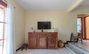 Una sala de estar con un aparador de madera, un televisor de pantalla plana y un sillón.
