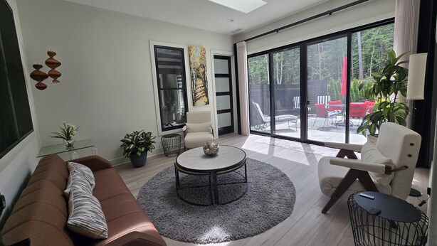 A modern living room with a brown sofa, a round coffee table, and a large sliding glass door leading to an outdoor area.