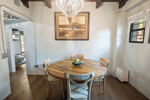 A dining area with a wooden table and chairs, a chandelier, and a framed picture on the wall.