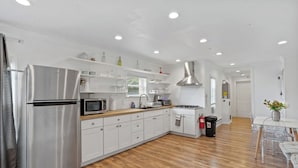 A modern kitchen with white cabinets, stainless steel appliances, and wooden flooring. - Spacious Modern Home near Ocean Resort + Boardwalk (Atlantic City)