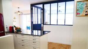 A kitchen with a black countertop, white cabinets, and a patterned rug. - Sublime appartement à 100m de la Croisette (Cannes)