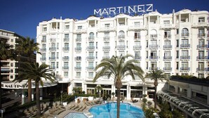 A hotel with a large swimming pool, palm trees, and a sign reading "MARTINEZ". - Sublime appartement à 100m de la Croisette (Cannes)