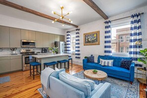 Una cocina moderna con una isla central, un sofá azul y una mesa de centro de madera.