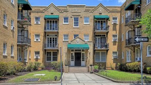 A brick building with a central entrance, multiple windows, and balconies.