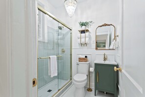 A bathroom with a glass-enclosed shower, a toilet, a sink, and a vanity cabinet.