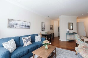 A living room with a blue sofa, a coffee table, and a dining area with a table and chairs.