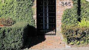 Un bâtiment à deux étages avec une entrée en briques, un balcon orné de balustrades en métal noir et un drapeau américain.
