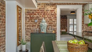 Een kamer met bakstenen muren, een groen kastje, een vaas en een mand appels.