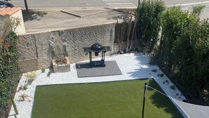 Eine Terrasse mit kleinem Rasen, Sitzgelegenheiten im Freien und einer Pergola.