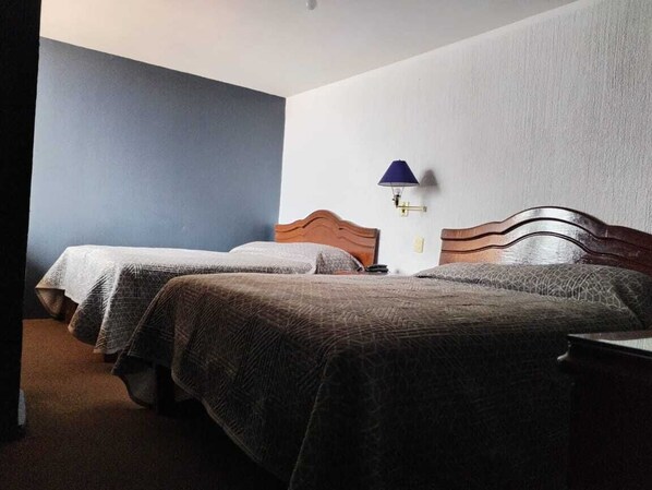 A hotel room with two single beds, a nightstand, a lamp, and a wall-mounted light fixture. - Hotel Guadalupe Express (Guadalupe)
