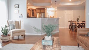 Un salon moderne avec une table basse en bois, un canapé beige et un coin repas comprenant une table et des chaises en bois.