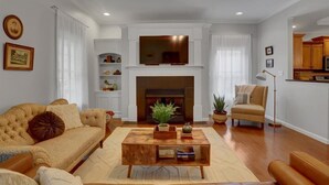 Un salon avec une cheminée, un canapé, une table basse et un téléviseur fixé au mur au-dessus de la cheminée.