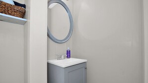 Ein Badezimmer mit einem weißen Waschbecken, einem Spiegel und einem Handtuchhalter.