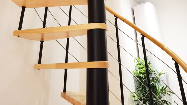 A spiral staircase with wooden steps and black metal railings.