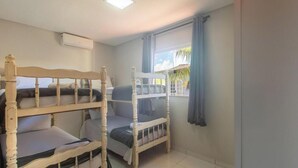 A room with bunk beds, a window with curtains, an air conditioning unit, and a tiled floor.