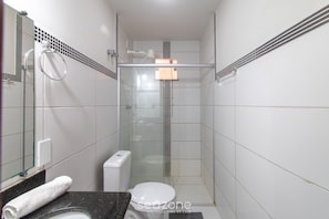 Uma casa de banho moderna com cabine de duche em vidro, sanita e lavatório com bancada de mármore.