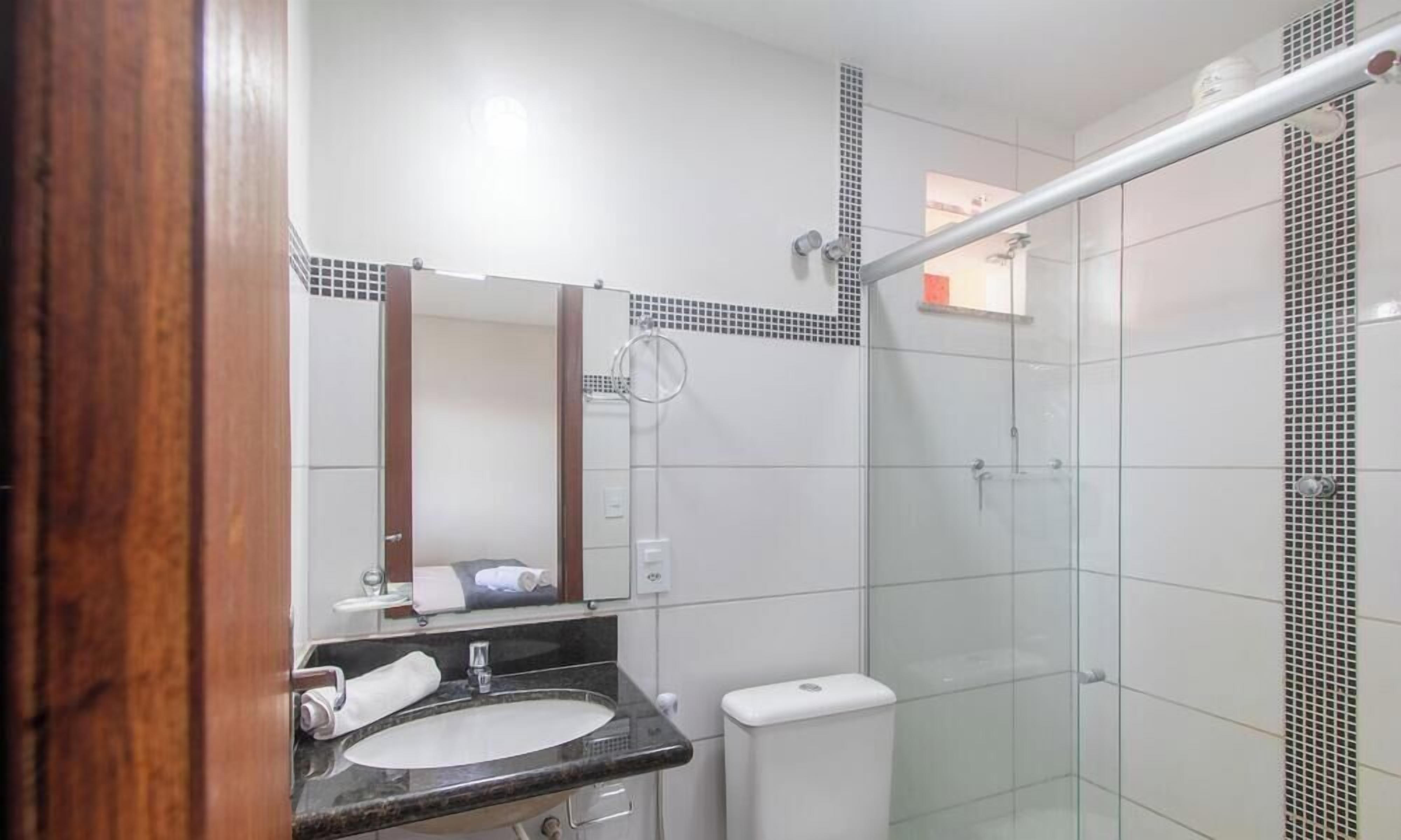 A bathroom with a sink, mirror, and shower.