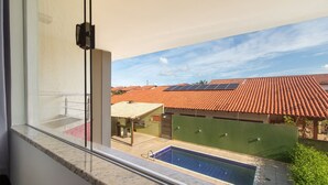 A view from a balcony with a swimming pool, solar panels, and terracotta roofs.