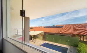 Blick vom Balkon auf einen Swimmingpool, Solaranlagen und Terrakottadächer.