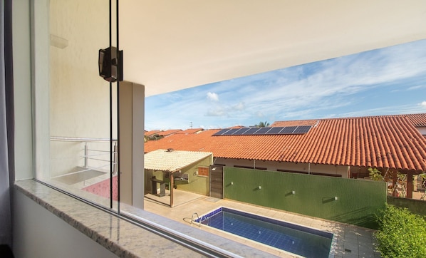 Vista de varanda com piscina, painéis solares e telhados de terracota.