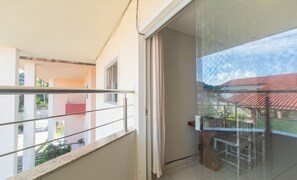 Ein Balkon mit Glastür, Metallgeländer und Blick auf ein Gebäude mit rotem Dach.