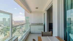 A balcony with a view of the city, a small kitchen area, and a dining table. - Estúdio em Cond no Setor Bueno CEL1804 (Goiânia)