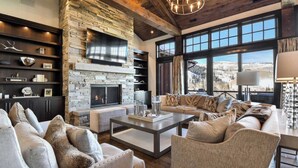 A spacious living room with a stone fireplace, large windows offering a mountain view, and a cozy seating area.