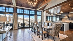 A spacious dining area with a view of a snowy landscape, wooden flooring, and modern furniture.