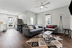 A modern living room with a grey sofa, a coffee table, and a patterned rug.