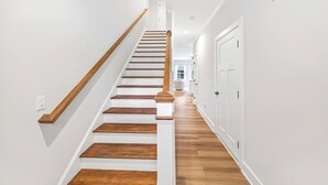 Eine Treppe mit Holzbodenstufen und einem Holzgeländer, die zu einer Zwischenebene mit einer weißen Tür führt.