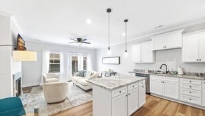 Una cucina moderna con mobili bianchi, un'isola in marmo e una ventola a soffitto.