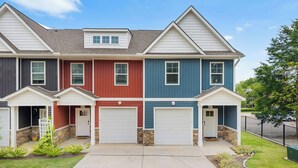 A row of townhouses with two garages each, a central entryway, and a small porch area. - New 2024 Townhome | Bright & Modern Stay Close to Downtown Spartanburg (Spartanburg)