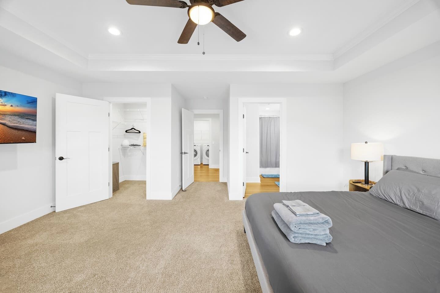 Une chambre à coucher avec un lit, un ventilateur de plafond, une table de chevet et un tableau accroché au mur.