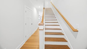 A staircase with wooden steps and a wooden handrail, leading to a door at the top. - New 2024 Townhome | Bright & Modern Stay Close to Downtown Spartanburg (Spartanburg)