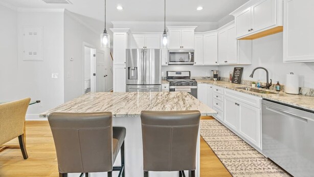 A modern kitchen with white cabinetry, stainless steel appliances, and a marble island. - New 2024 Townhome | Bright & Modern Stay Close to Downtown Spartanburg (Spartanburg)