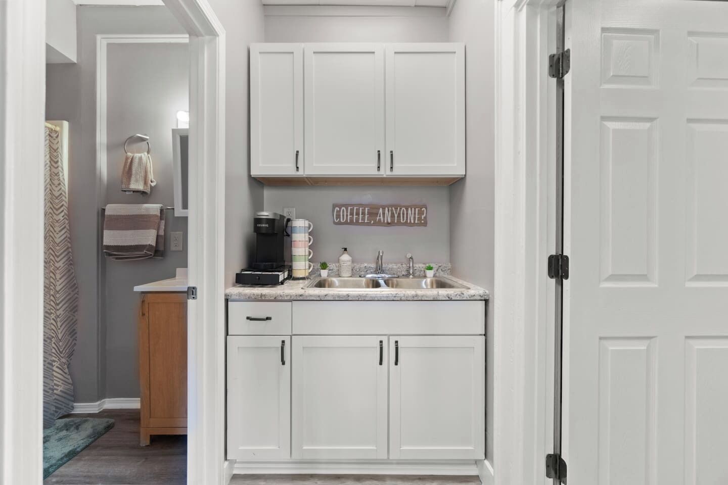 A kitchen with white cabinets, a coffee maker, and a sink.