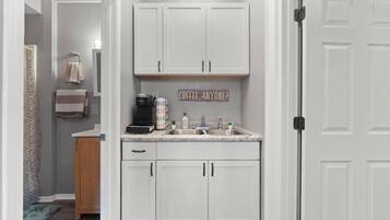 A kitchen with white cabinets, a coffee maker, and a sink.